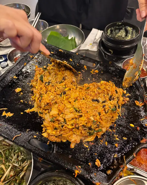 철판 위에서 볶아지고 있는 김치볶음밥의 먹음직스러운 모습