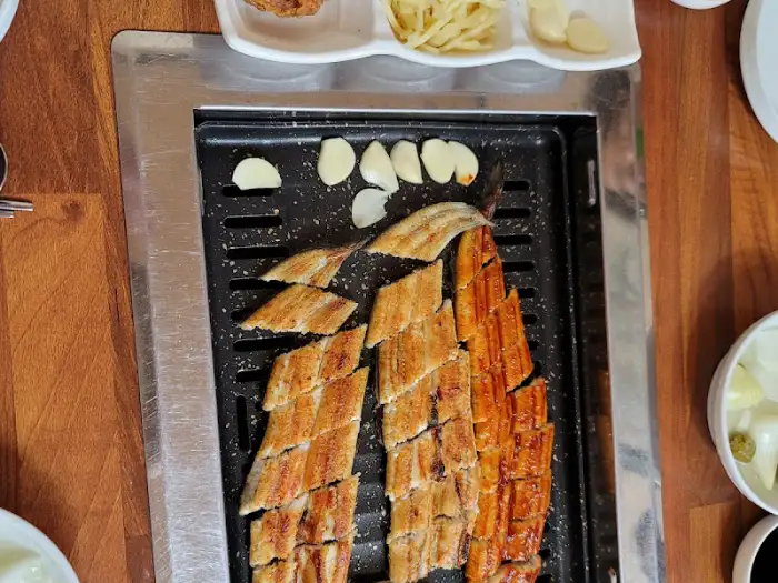 기찬민물장어에서 갓 구워낸 두툼한 장어구이와 곁들임 찬