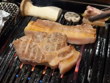 숯불 위에서 맛있게 익어가는 마장동김씨 명촌맛집점의 삼겹살과 버섯
