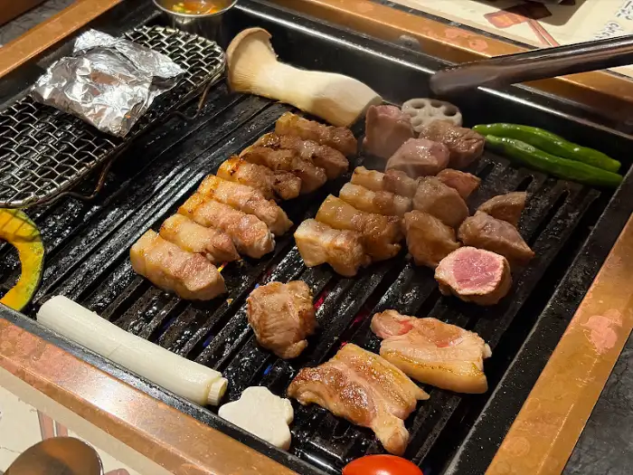 마장동김씨 명촌맛집점의 숯불 위에서 맛있게 익어가는 삼겹살과 다양한 곁들임