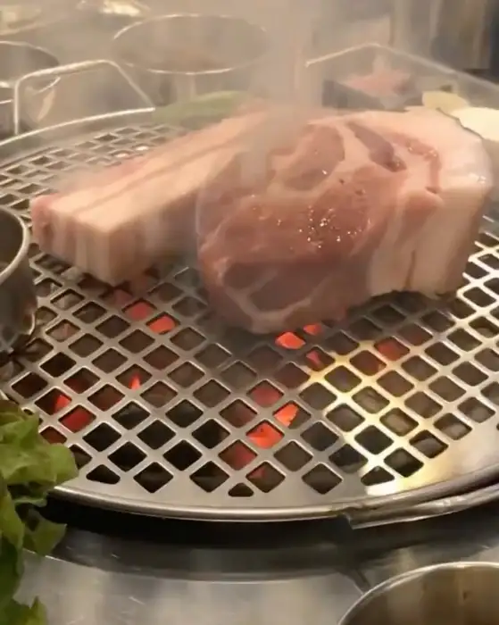 숯불 위에서 맛있게 구워지고 있는 두툼한 제주 흑돼지