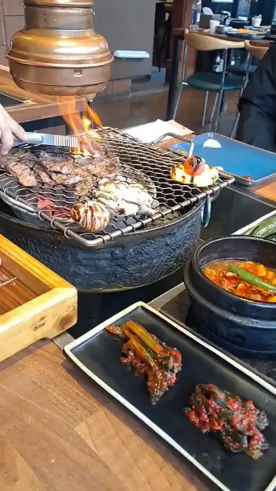 숯불 위에서 맛있게 익어가는 고기와 곁들임 메뉴