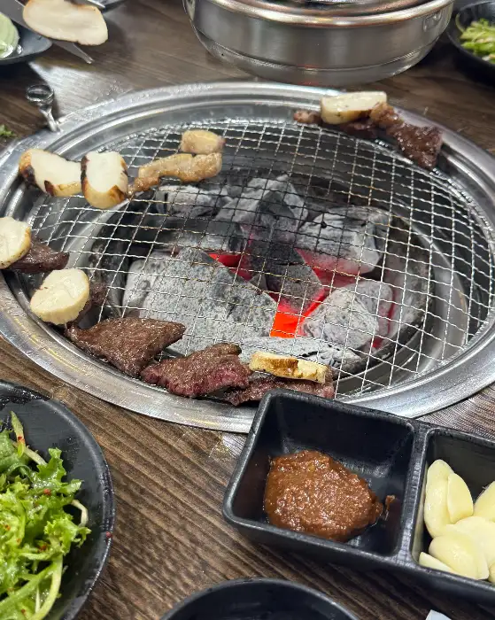 숯불 위에서 익어가는 고기와 곁들임 반찬