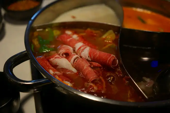 훠궈 냄비에 담긴 붉은 국물과 얇게 썬 양고기