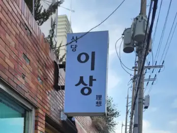 이상식당 간판, 파란색 바탕에 검은색 한글로 상호명이 적혀 있습니다.