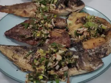 명촌식당의 푸짐한 생선구이 한 접시, 다양한 종류의 생선과 양념이 먹음직스럽게 담겨 있습니다.