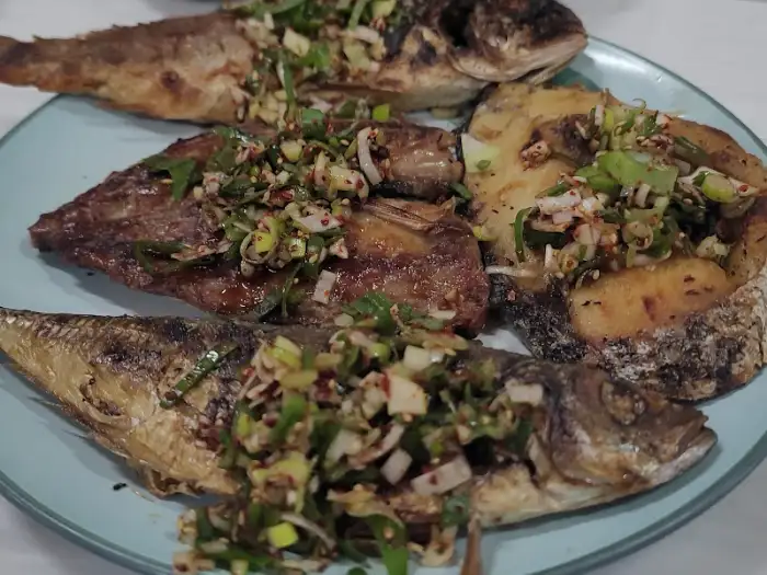 명촌식당의 푸짐한 생선구이 한 접시, 다양한 종류의 생선과 양념이 먹음직스럽게 담겨 있습니다.