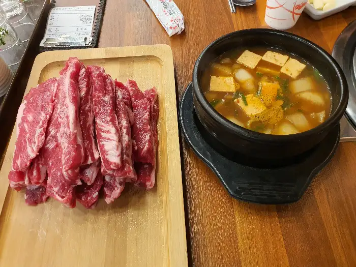 한 접시에 담긴 생고기 덩어리와 김치찌개