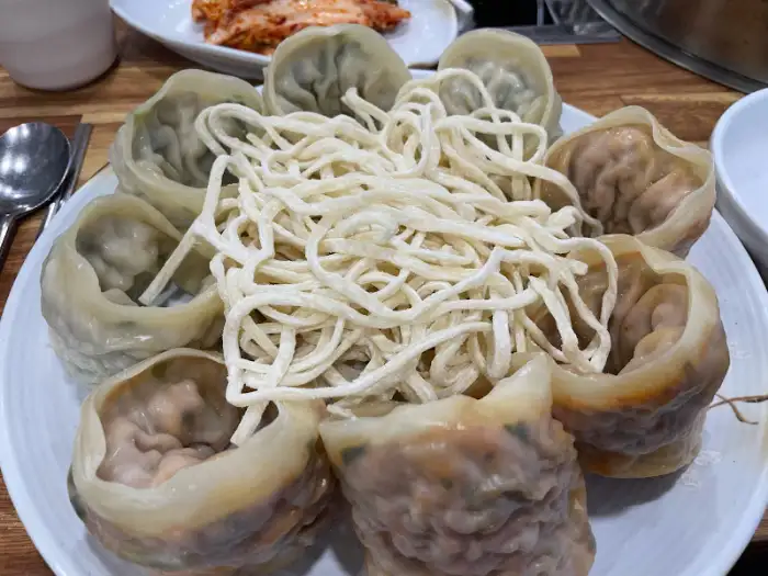 한 접시에 담긴 큼직한 만두와 국수 가닥들