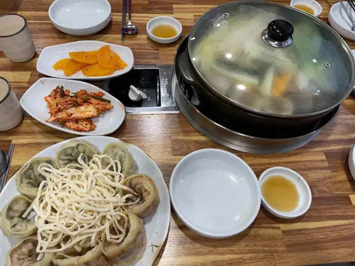 식탁 위에 놓인 전골 냄비와 곁들임 찬들