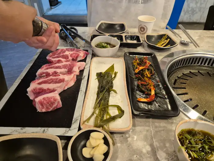 정갈하게 차려진 밑반찬과 신선한 고기가 놓인 모습