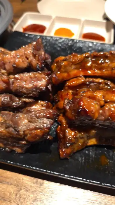 접시에 담긴 다양한 맛의 쪽갈비들. 간장 양념, 매콤한 양념 등이 섞여 있으며, 곁들임 소스와 함께 제공된다.