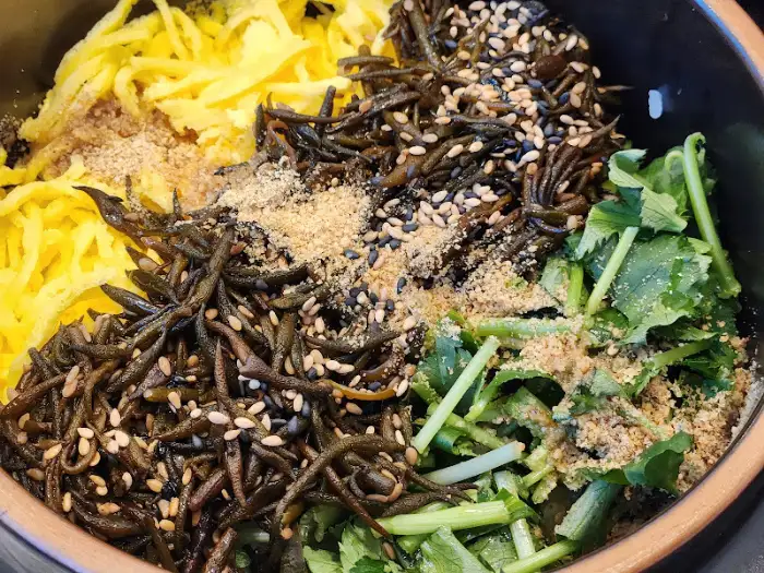 밥 위에 여러 가지 나물과 계란 지단이 올려져 있는 모습
