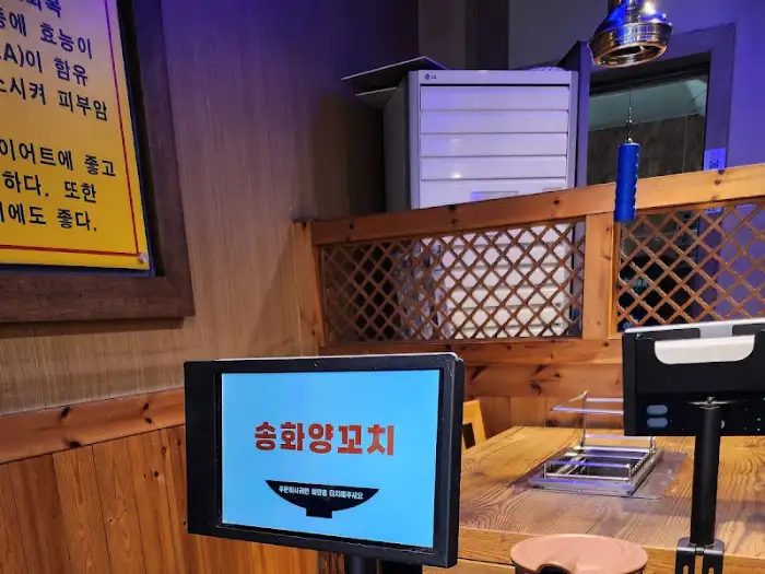 테이블 위 모니터에 송화양꼬치 상호명이 뜬 모습