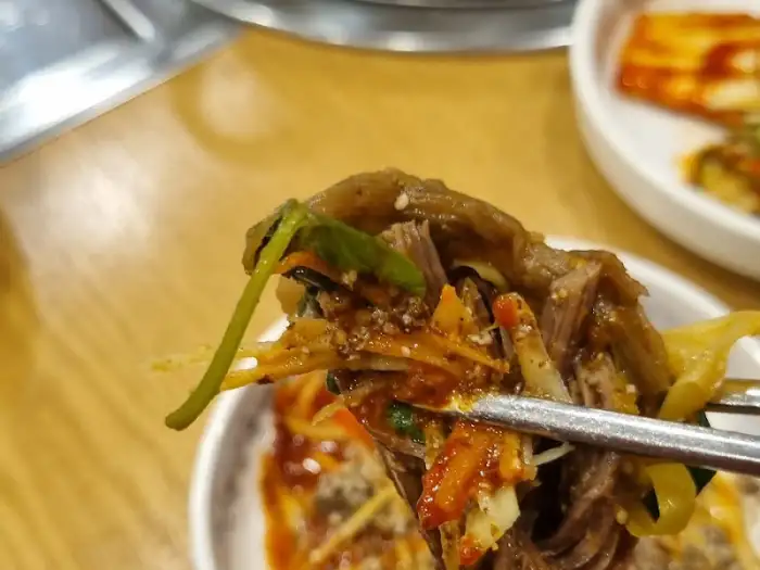 흑염소 요리 한 점을 집는 모습