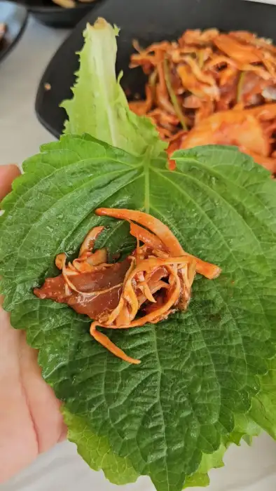 신선한 깻잎에 멸치회무침을 올려 싸 먹는 모습