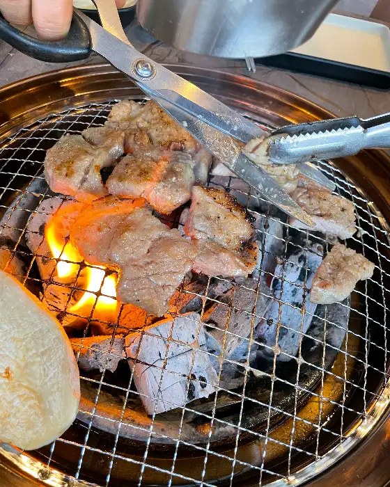 숯불 위에서 지글지글 익어가는 두툼한 돼지갈비 조각들