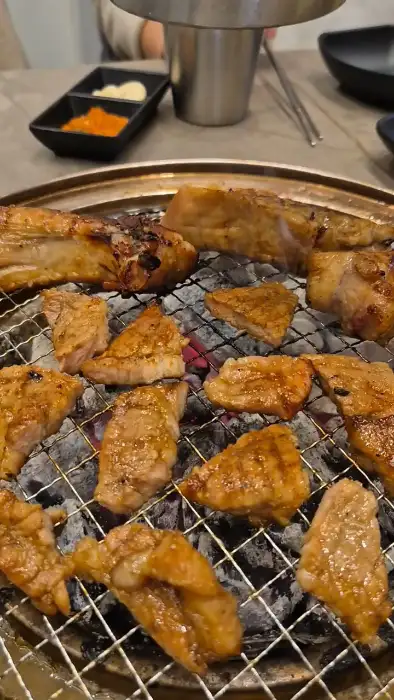 갈빗대와 함께 가지런히 놓인 돼지고기 조각들이 숯불 위에서 익어가고 있는 모습