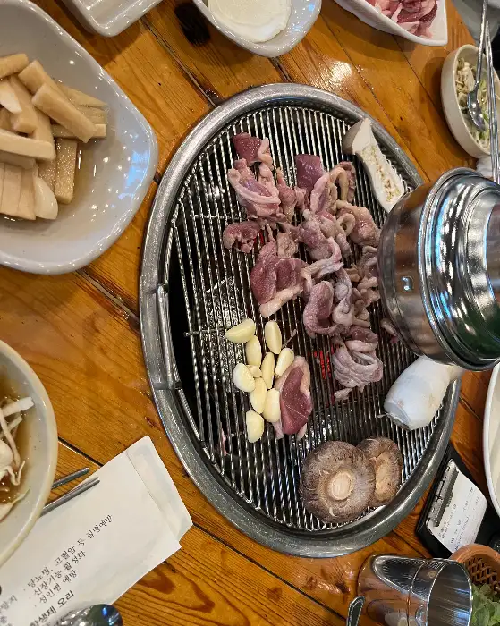불판 위에 올려진 오리고기와 마늘, 버섯