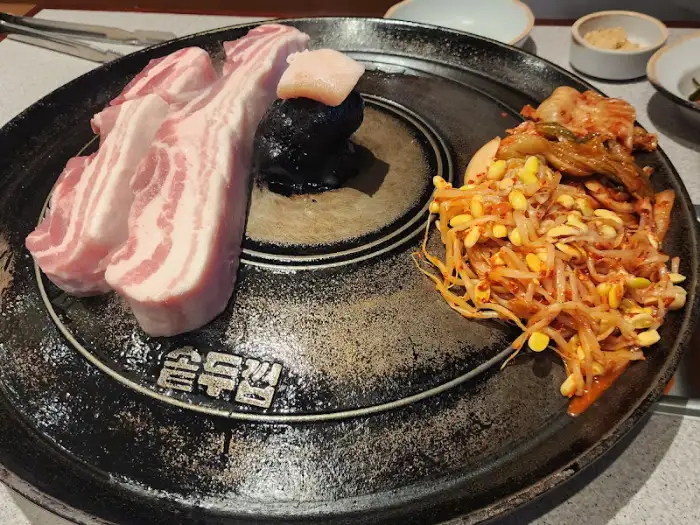 솥뚜껑 위에서 익기 시작하는 삼겹살과 콩나물 무침