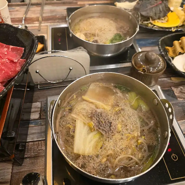 끓고 있는 샤브샤브 육수에 채소를 넣고 있는 모습