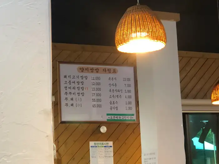 순천 양지 생선구이 내부 메뉴판과 조명, 벽에 걸린 메뉴판과 따뜻한 느낌의 등불 조명이 보인다.