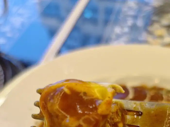 포크에 얹힌 매콤한 소스의 돈까스 조각