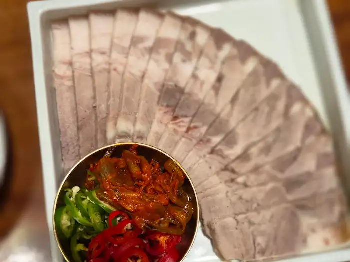 정갈하게 겹쳐진 수육과 함께 나오는 새우장, 고추, 깻잎