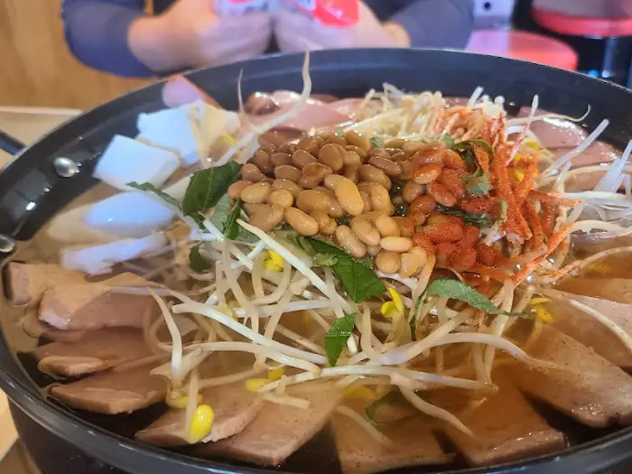 부대찌개 냄비 안에는 떡, 콩나물, 햄, 어묵, 두부 등 다양한 재료가 꽉 차 있습니다.