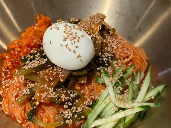 흰자와 노른자가 분리된 계란 프라이가 올라간 비빔국수