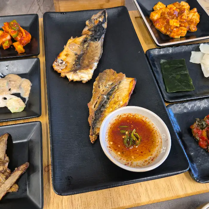 구워진 생선 두 조각과 매콤한 소스가 담긴 그릇