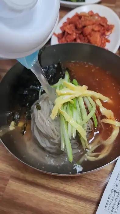 막국수에 시원한 동치미 육수를 붓는 모습