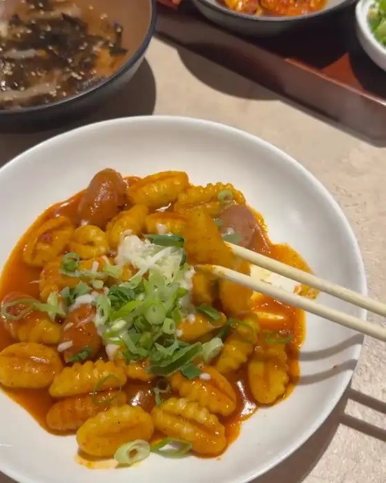 젓가락으로 집어 올린 뇨끼 떡볶이 한 조각