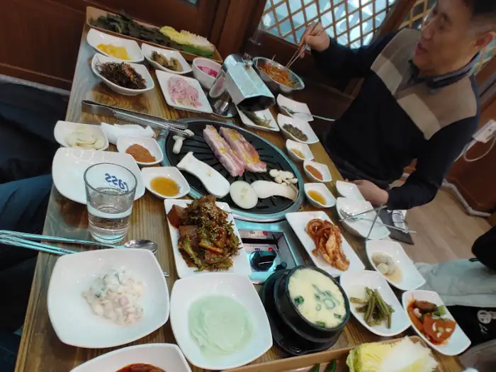 직원이 고기를 구워주고 있는 모습과 푸짐하게 차려진 식탁