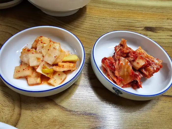 작은 그릇에 담긴 두 종류의 김치: 깍두기와 배추김치