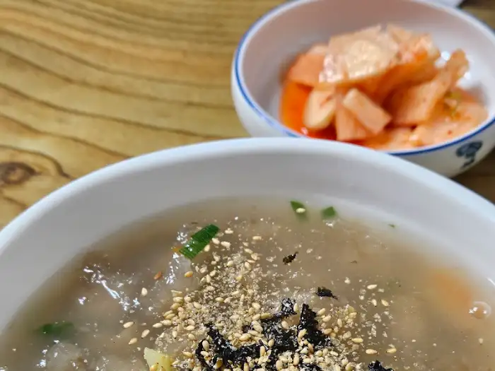옹심이 칼국수 위 고명으로 올라간 김가루와 참깨