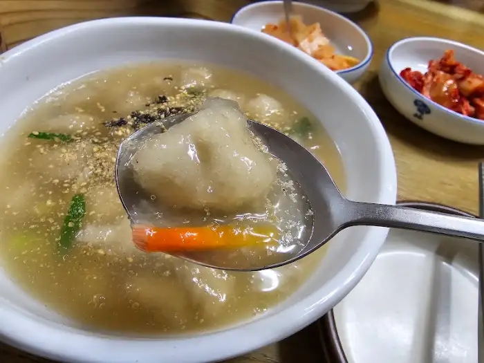 김이 모락모락 나는 옹심이 칼국수 한 그릇과 숟가락에 담긴 옹심이