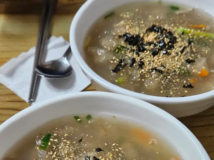 테이블에 놓인 옹심이 칼국수 두 그릇과 젓가락, 냅킨