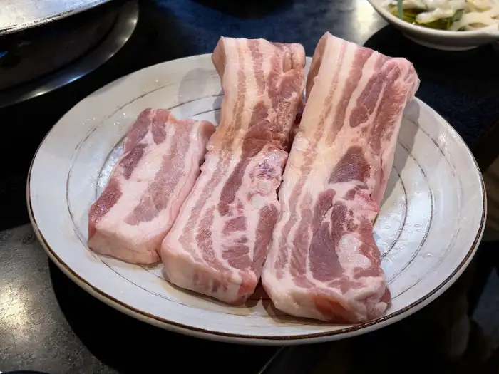 전주하우스 불판에 올려진 신선한 삼겹살 덩어리