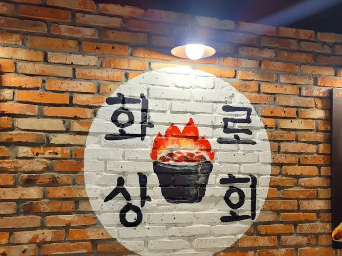 식당 외벽에 그려진 붉은 불꽃과 솥 그림이 있는 원형 로고