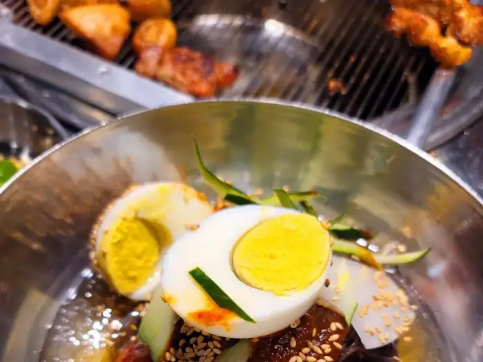 고기 불판 위에 계란찜이 올려져 있고, 그 옆에는 익은 고기들이 보인다.
