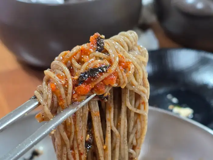 집게로 집어 올린 막국수 면발