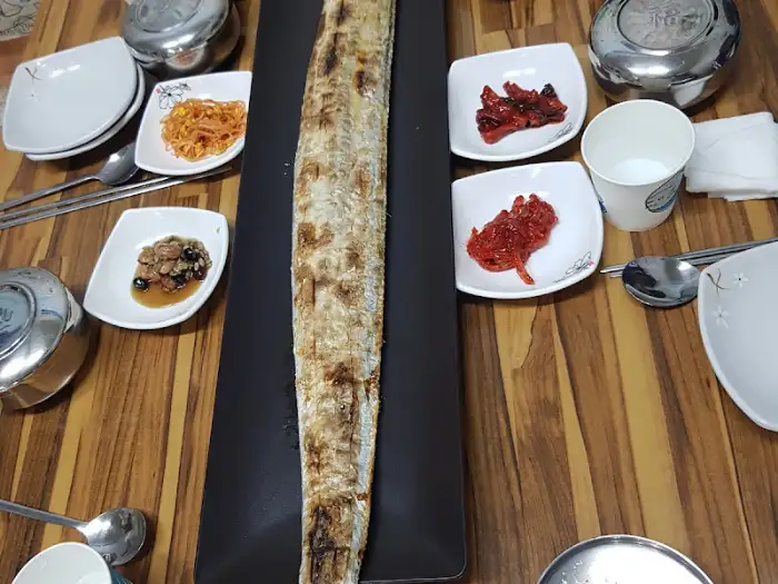 테이블 위에 놓인 통갈치구이의 클로즈업 사진, 겉면이 노릇하게 구워져 있습니다.