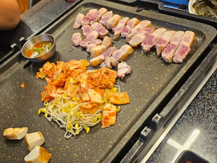 돌판 위에서 맛있게 익어가는 삼겹살의 모습입니다.