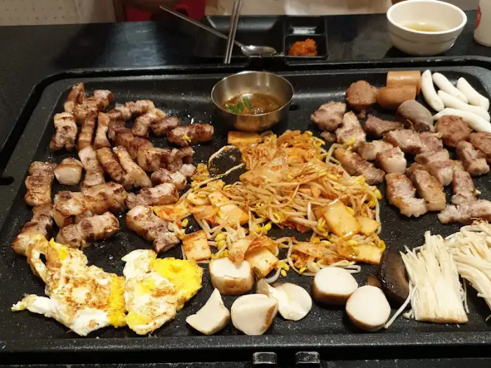 돌판 위에 계란 프라이, 떡, 버섯 등 다양한 재료가 올려져 익어가고 있습니다.