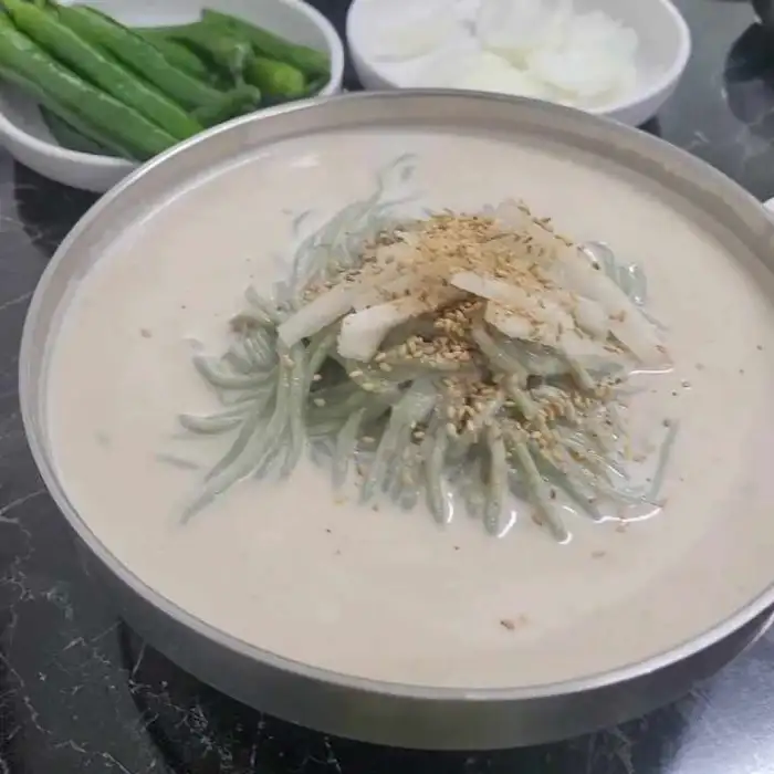 콩국물 위에 쑥면과 고명이 얹어진 콩국수 모습