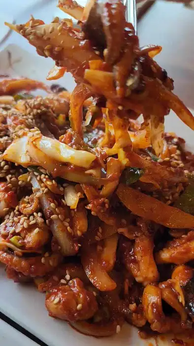 집게로 들어 올린 먹음직스러운 쭈꾸미 볶음