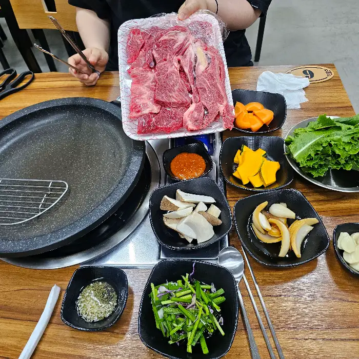 식탁 위에 차려진 고기와 다양한 반찬, 그리고 불판