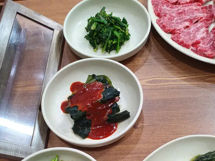 정갈하게 차려진 한우 식당의 밑반찬들, 푸른 나물 무침과 붉은 양념의 묵은지