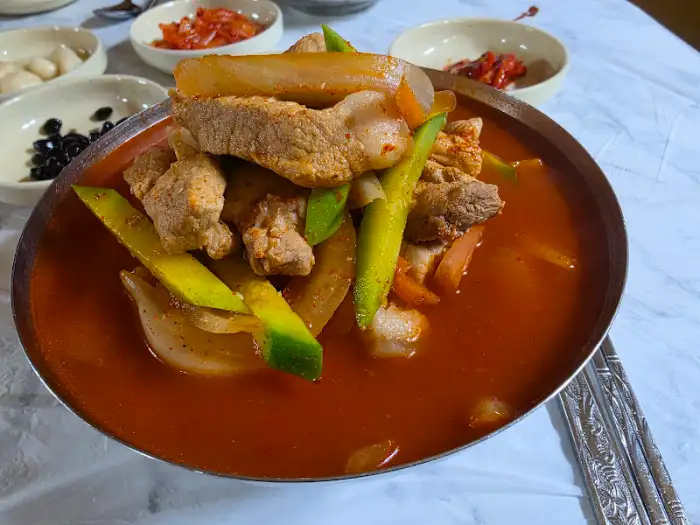 명화식육식당의 푸짐한 메인 요리, 국물과 고기, 채소가 가득 담겨 있습니다.